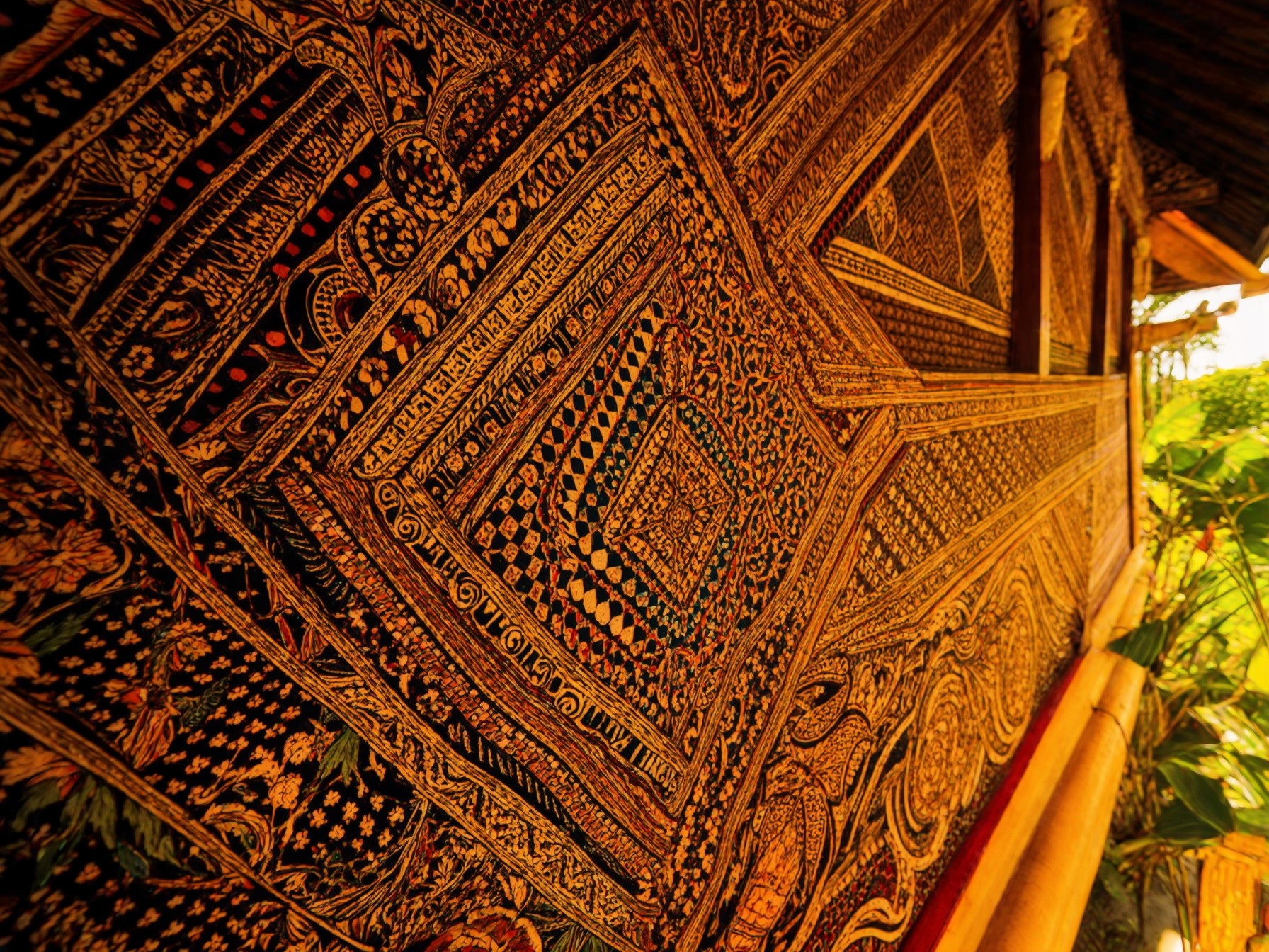 Intricate traditional Thai temple wall art with detailed gold and black patterns, showcasing cultural craftsmanship.