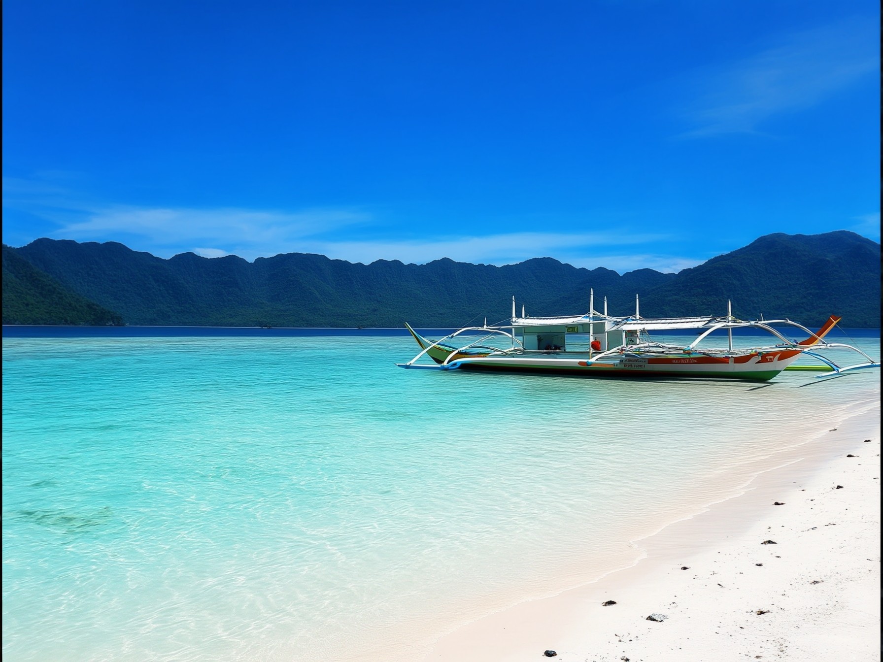 Traditional boat on a tropical white sand beach with crystal clear turquoise water and mountainous backdrop under a clear blue sky.