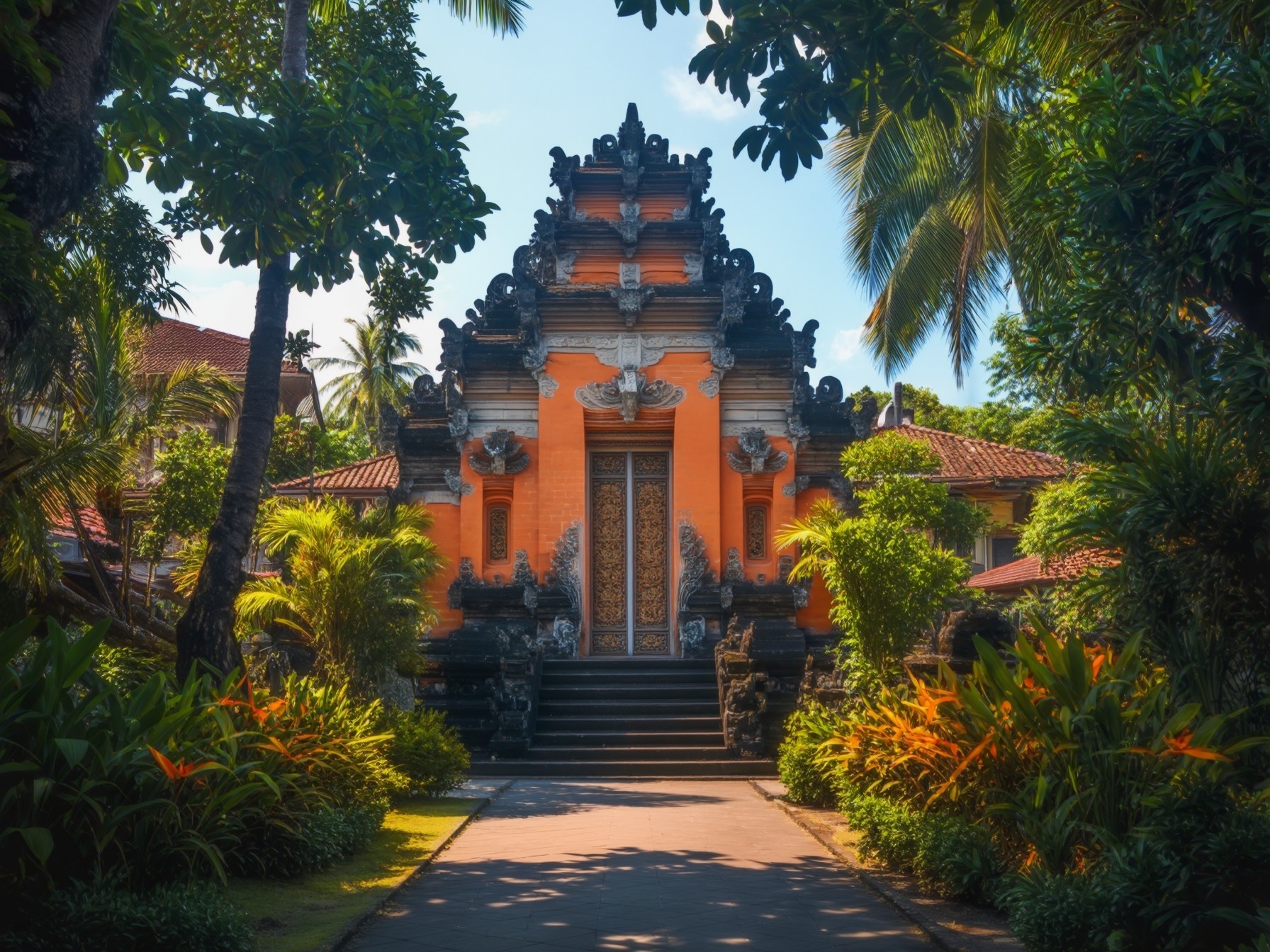 Traditional Balinese temple entrance surrounded by lush green foliage and tropical plants, showcasing intricate architectural details.