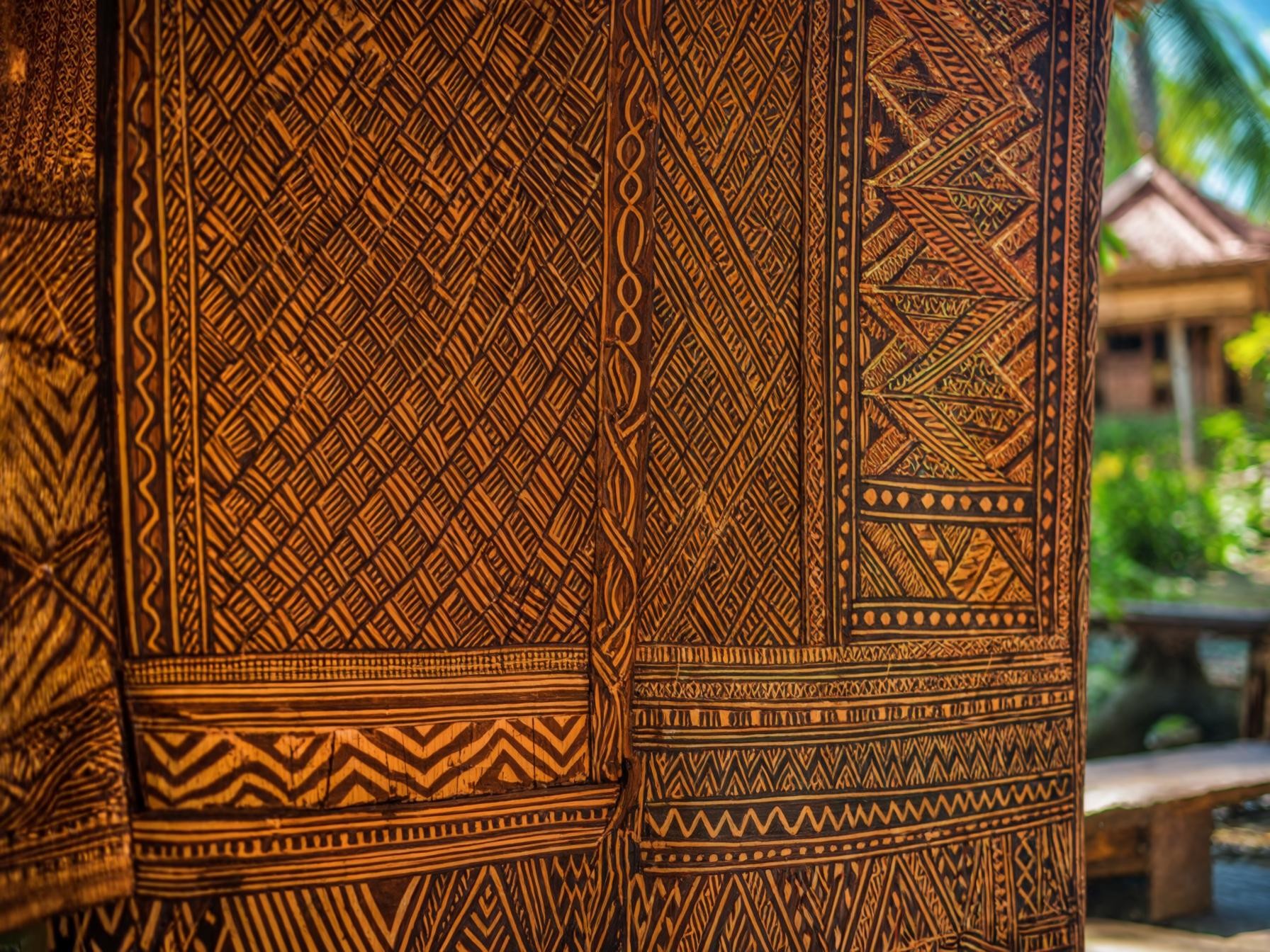 Traditional Tongan tapa cloth with intricate geometric patterns displayed outdoors.