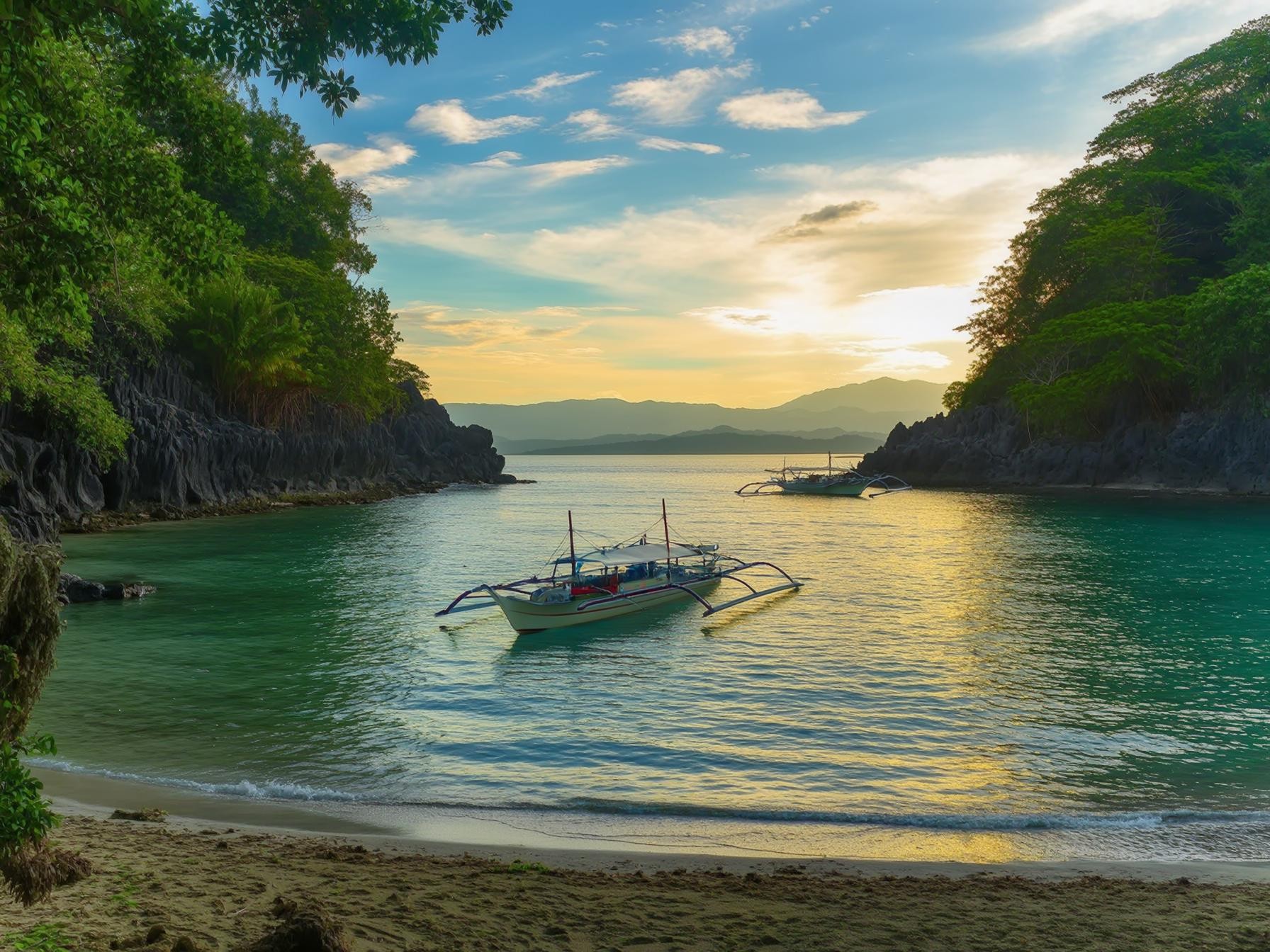 Peaceful beach cove with colorful boats and lush greenery at sunset.